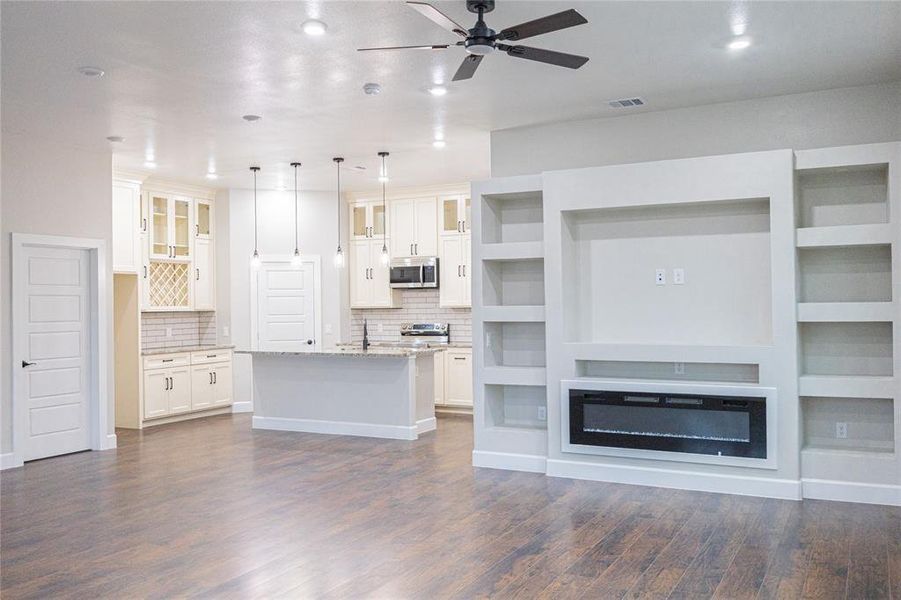 Unfurnished living room with a ceiling fan and dark wood-style flooring Unfurnished living room with a ceiling fan and dark wood-style flooring