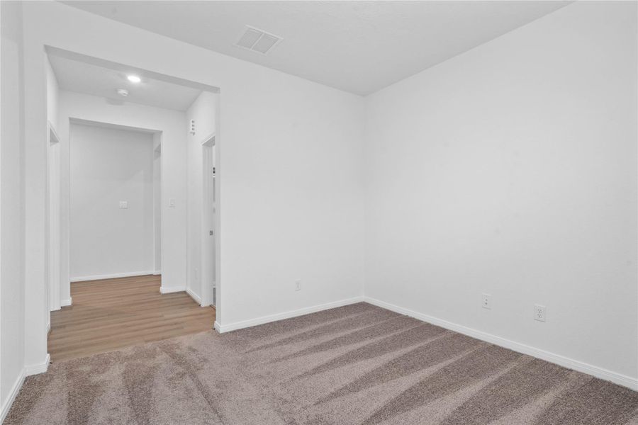 Additional view from Den looking out to the hallway that leads one to the primary bedroom suite on the left and the laundry room on the right.