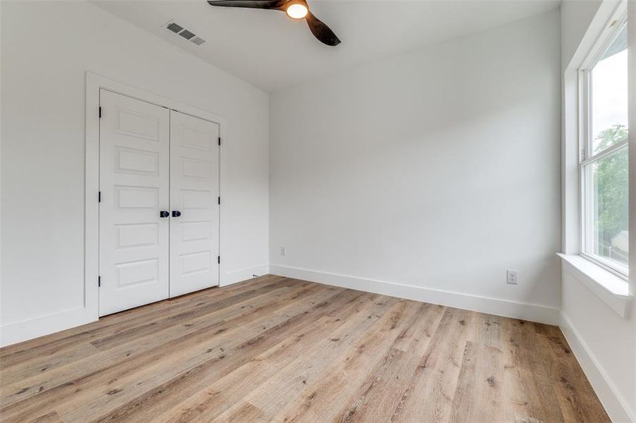 Second bedroom with wood finished floors, a closet, ceiling fan, baseboards, and visible vents