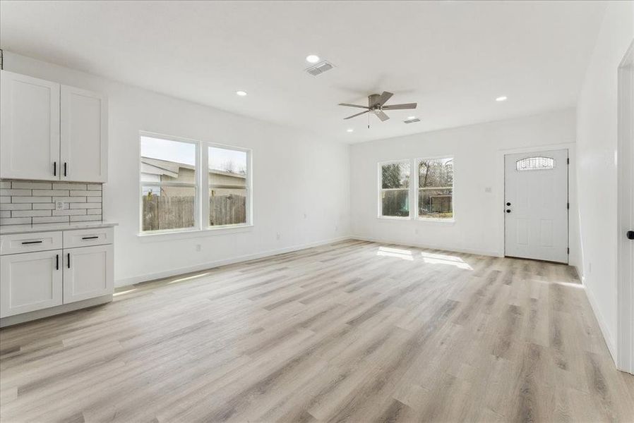 Unfurnished living room with light wood-style flooring, visible vents, baseboards, and recessed lighting