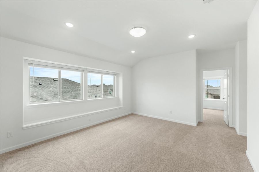 Empty bedroom with beige carpet, white walls, recessed lighting, and a large window
