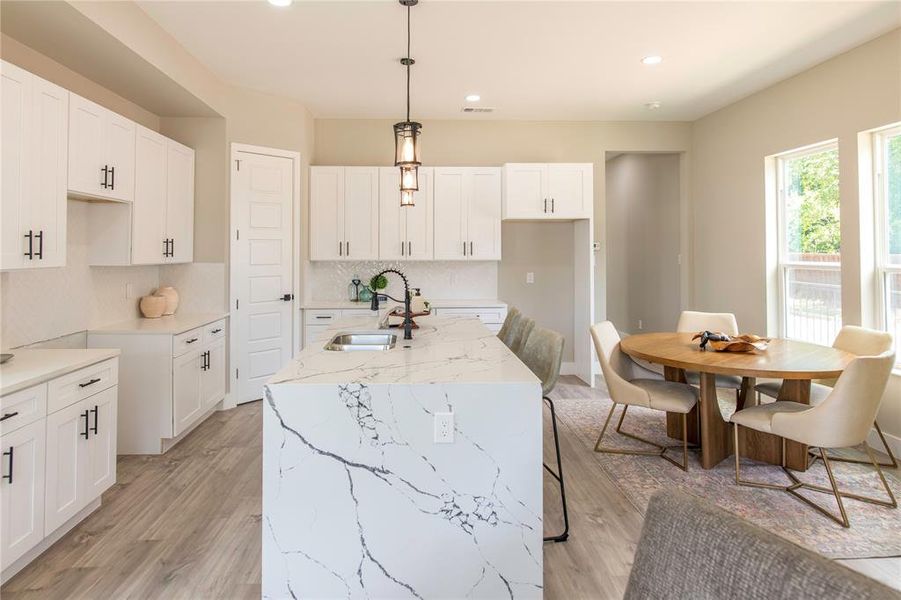 Kitchen featuring light hardwood / wood-style flooring, tasteful backsplash, an island with sink, sink, and white cabinets