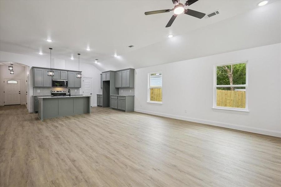 Unfurnished living room with lofted ceiling, light wood-type flooring, arched walkways, a ceiling fan, and recessed lighting Unfurnished living room with lofted ceiling, light wood-type flooring, arched walkways, a ceiling fan, and recessed lighting
