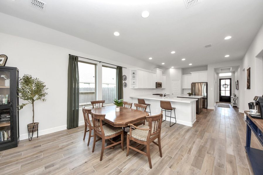 This photo highlights an open-concept kitchen and living area. White cabinets, stainless steel appliances, and a central island define the kitchen, while the adjoining living space is filled with natural light, wood flooring, and comfortable seating, perfect for entertaining or relaxing.