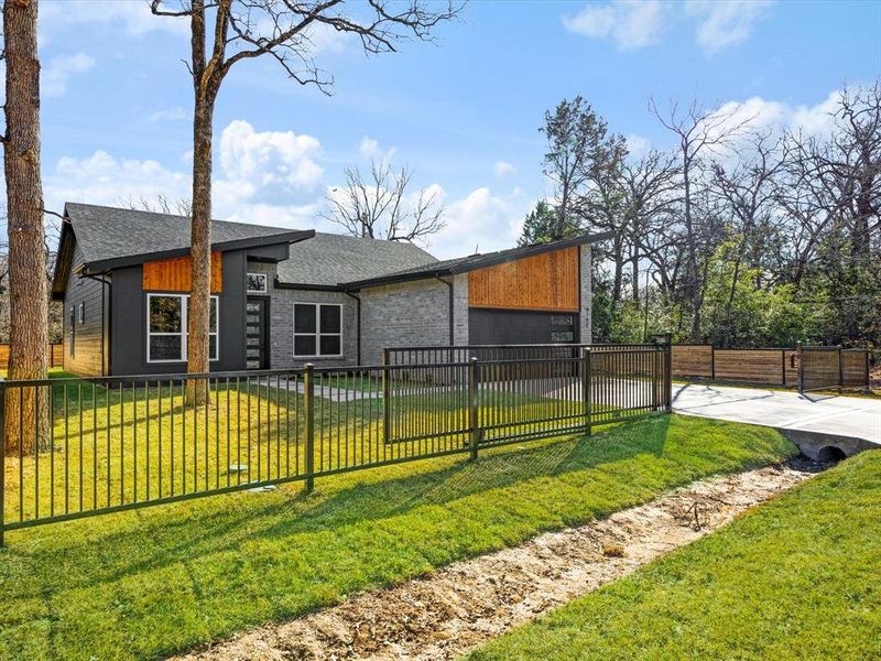 View of front of home featuring a fenced front yard, a garage, driveway, and a shingled roof