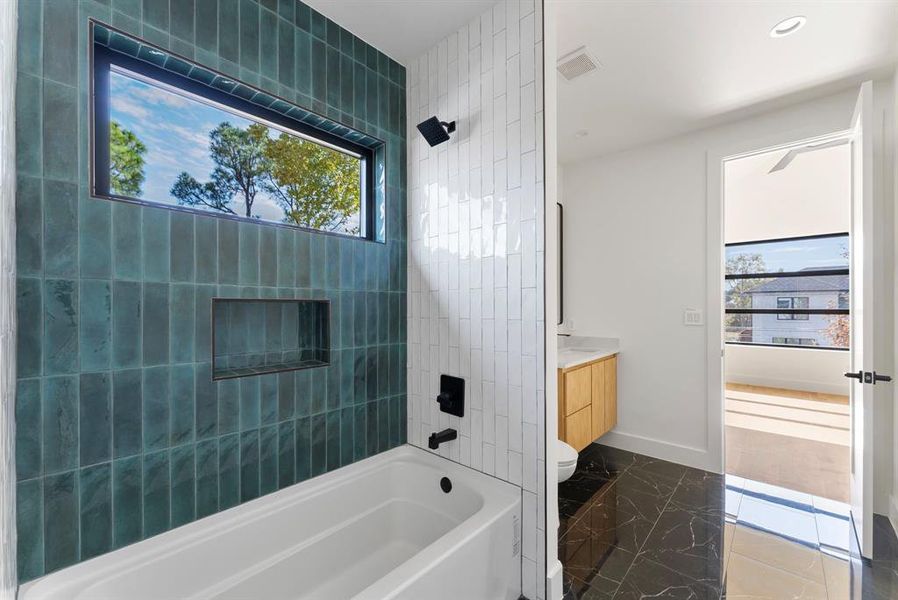 Bathroom with vanity, natural light, tub / shower combination, and dark marble finish flooring Bathroom with vanity, natural light, tub / shower combination, and dark marble finish flooring