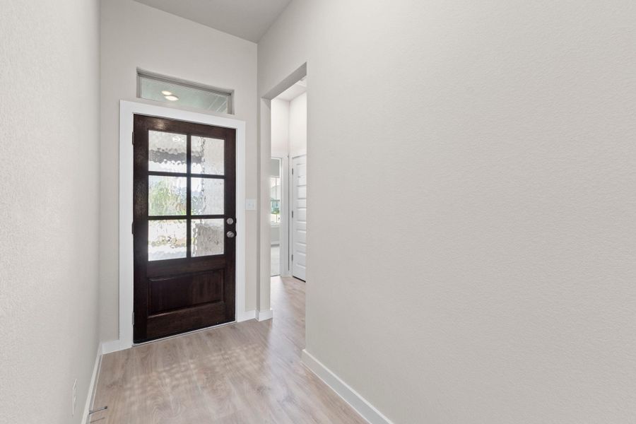 A classic dark wood front door with frosted glass panels welcomes you into this inviting home.
