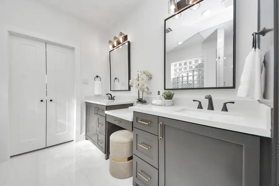 This bathroom features a sleek double vanity with black fixtures and ample storage. Neutral tones, large mirrors, and contemporary lighting contribute to a bright, elegant environment. This bathroom features a sleek double vanity with black fixtures and ample storage. Neutral tones, large mirrors, and contemporary lighting contribute to a bright, elegant environment.