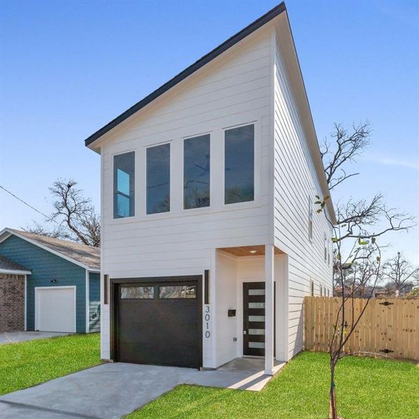 Contemporary home featuring a front yard and a garage