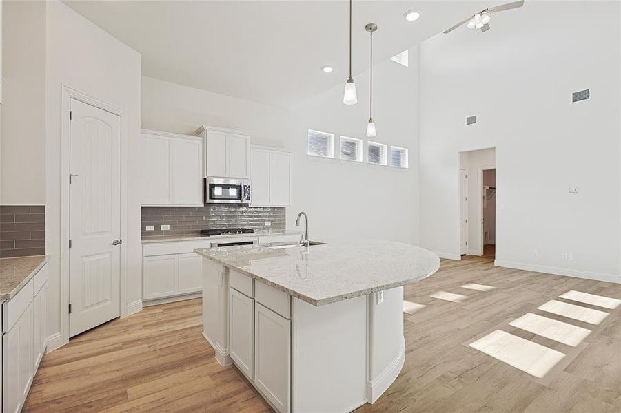 Kitchen featuring backsplash, white cabinetry, an island with sink, and appliances with stainless steel finishes