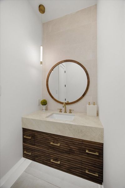 The powder room involves a statement mirror paired with elegant pendant lighting creates a moment of understated sophistication.