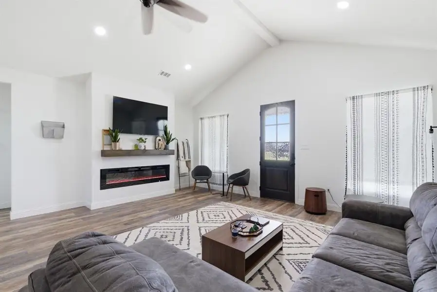 Living area featuring light wood-type flooring, a ceiling fan, a glass covered fireplace, and recessed lighting Living area featuring light wood-type flooring, a ceiling fan, a glass covered fireplace, and recessed lighting