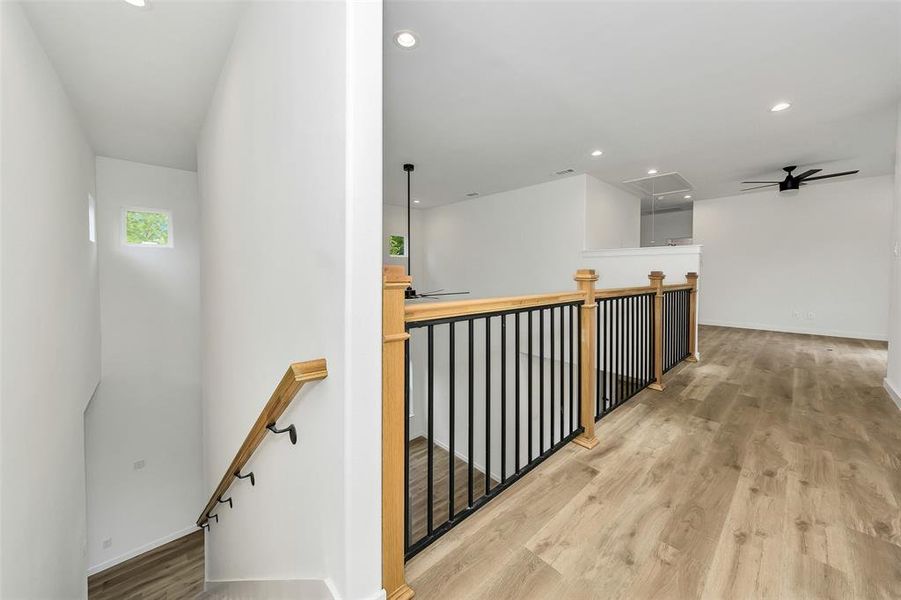 Hallway with an upstairs landing, attic access, wood finished floors, recessed lighting, and baseboards Hallway with an upstairs landing, attic access, wood finished floors, recessed lighting, and baseboards