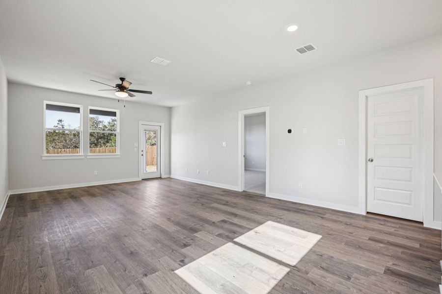 A room with a wood floor and a wood floor with a fan.