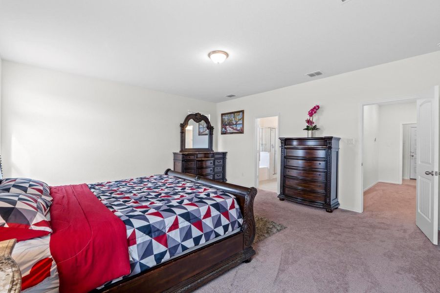 Spacious room featuring neutral wall paint, carpet flooring, a ceiling-mounted light fixture, and two open doorways revealing additional interior spaces