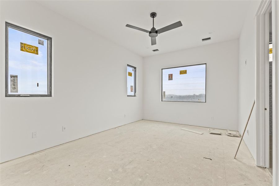 Spacious room with multiple windows, featuring a modern ceiling fan, recessed lighting, and a neutral white color palette