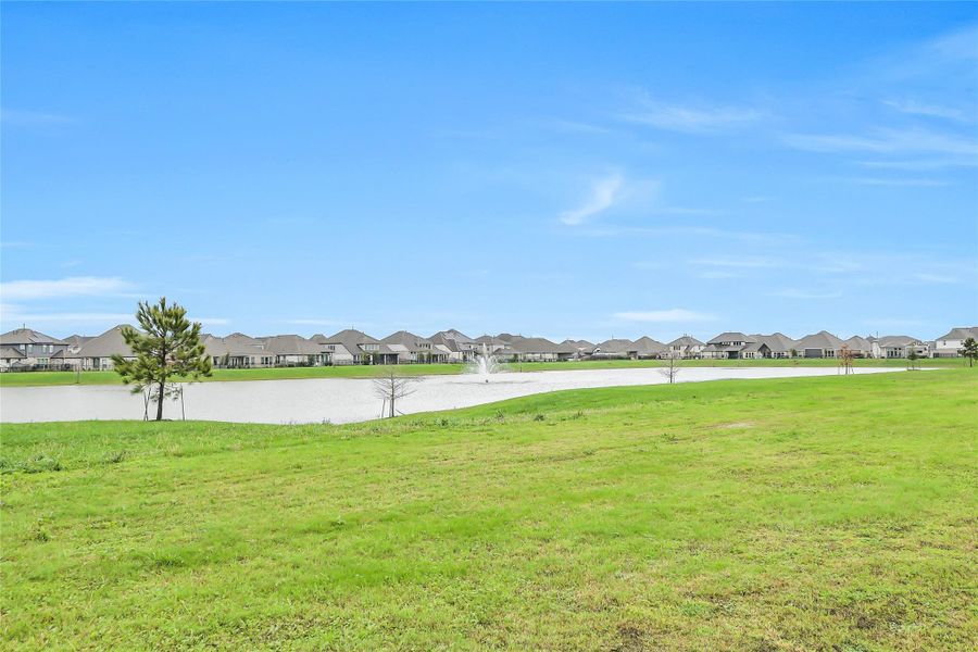 Peaceful lake view just beyond the backyard, featuring a scenic community pond with fountain and expansive green space—creating a serene backdrop and enhancing the home’s outdoor lifestyle appeal.