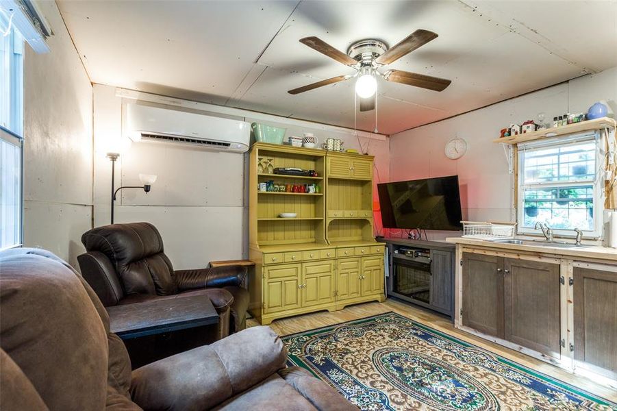 Living room featuring ceiling fan, light hardwood / wood-style flooring, sink, and a wall mounted AC