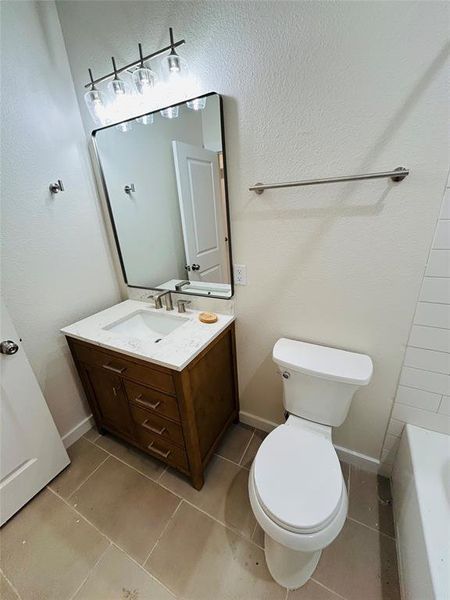 Bathroom with tile patterned flooring, vanity, toilet, and a bathtub