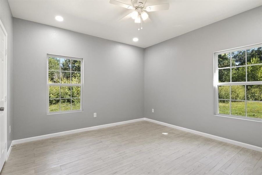 Empty room with healthy amount of natural light, light wood finished floors, recessed lighting, and a ceiling fan