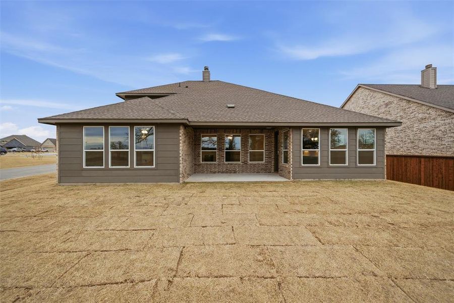 Back of house with roof with shingles, a patio, and a chimney