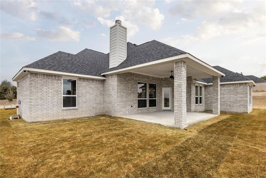 Rear view of property featuring a lawn and a patio area