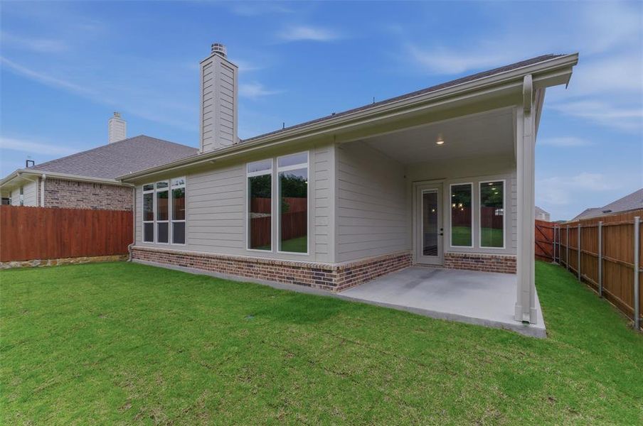 Rear exterior featuring a covered patio, a brick and siding facade, and multiple windows