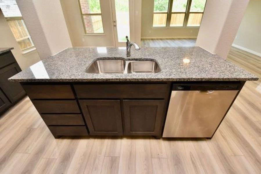 Kitchen featuring dishwasher, dark brown cabinetry, granite countertops, and light wood-style flooring Kitchen featuring dishwasher, dark brown cabinetry, granite countertops, and light wood-style flooring