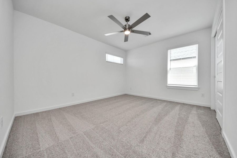 Secondary bedroom features plush carpeting, large windows that let in plenty of natural light, bright paint, and spacious closets. Sample photo of completed home with similar floor plan. Actual colors and selections may vary.