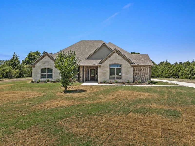 French country style house featuring a front yard, a garage, driveway, and brick siding French country style house featuring a front yard, a garage, driveway, and brick siding