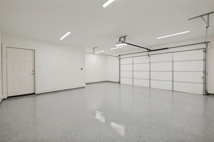 Spacious rear-entry two-car garage featuring an epoxy-coated floor, a dedicated storage nook, and a side-yard access door. Spacious rear-entry two-car garage featuring an epoxy-coated floor, a dedicated storage nook, and a side-yard access door.