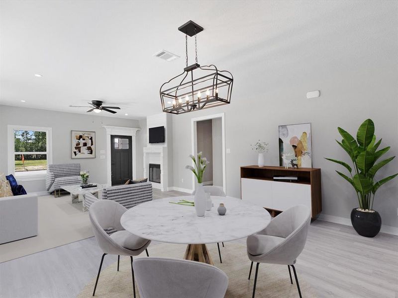 Dining area with light wood-style flooring, a ceiling fan, a glass covered fireplace, baseboards, and a chandelier