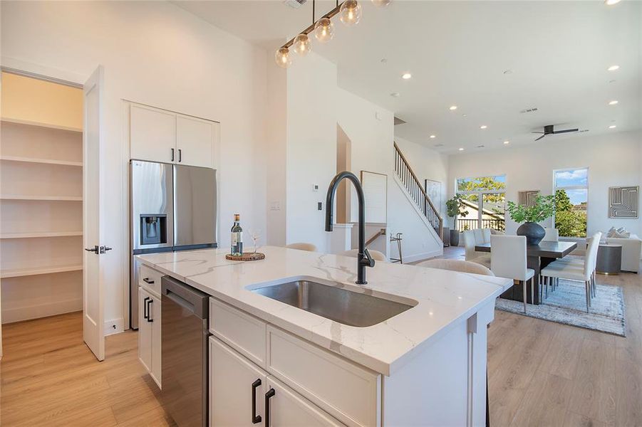 Kitchen with open floor plan, white cabinets, recessed lighting, light stone counters, and light wood-type flooring Kitchen with open floor plan, white cabinets, recessed lighting, light stone counters, and light wood-type flooring