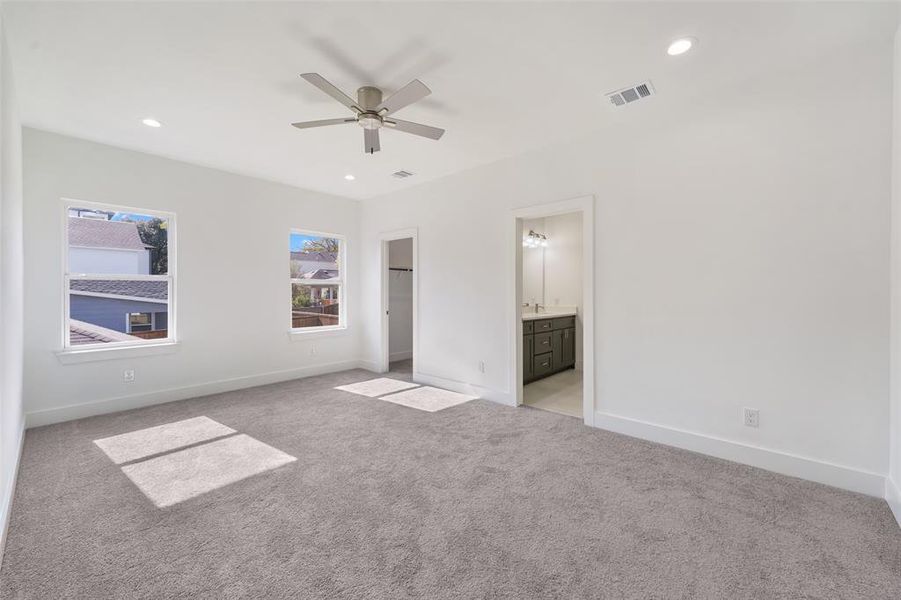 Unfurnished bedroom featuring a spacious closet, light colored carpet, recessed lighting, a ceiling fan, and connected bathroom