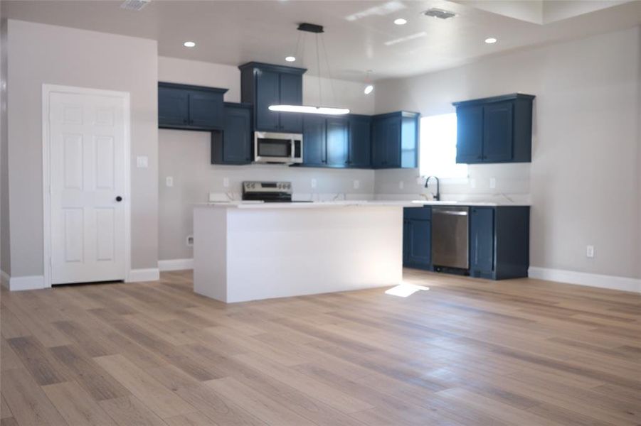 Kitchen with light countertops, appliances with stainless steel finishes, light wood finished floors, decorative light fixtures, and recessed lighting Kitchen with light countertops, appliances with stainless steel finishes, light wood finished floors, decorative light fixtures, and recessed lighting