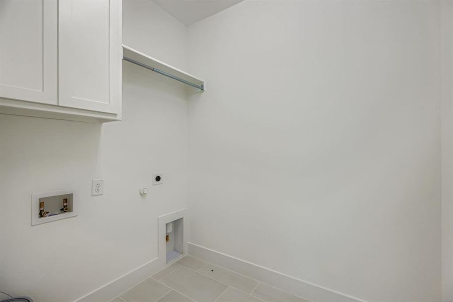 Laundry area featuring light tile patterned flooring, hookup for a gas dryer, cabinet space, electric dryer hookup, and washer hookup Laundry area featuring light tile patterned flooring, hookup for a gas dryer, cabinet space, electric dryer hookup, and washer hookup