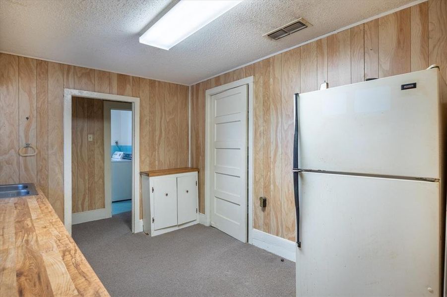 Kitchen with white refrigerator, washer / dryer, wooden counters, and wooden walls