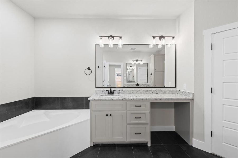 Full bathroom featuring vanity, a garden tub, and dark tile patterned flooring Full bathroom featuring vanity, a garden tub, and dark tile patterned flooring