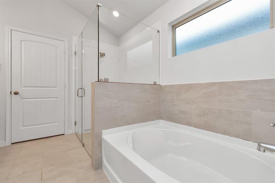 Indulge in a spa-like experience with this primary bathroom’s deep soaking tub and separate glass-enclosed shower. The elegant tile work and clean lines combine to offer a calming and contemporary ambiance. **This image is from another Saratoga Home - Clover floorplan.**