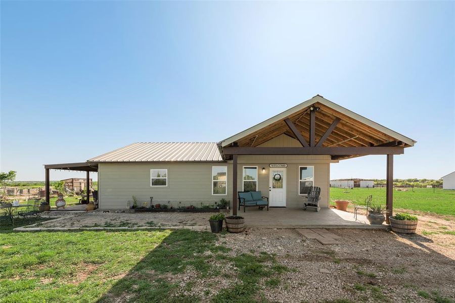 Back of house with a yard, a patio, and metal roof
