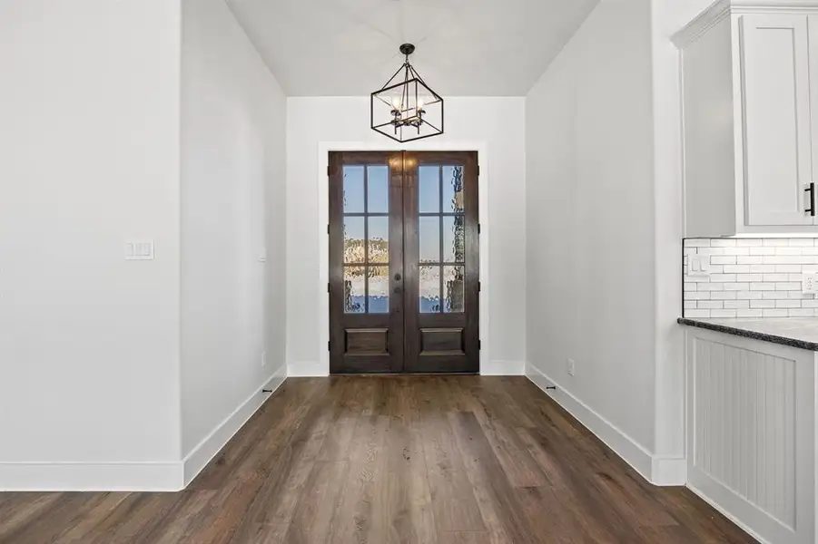 Entrance foyer with dark wood-style flooring, french doors, and a chandelier