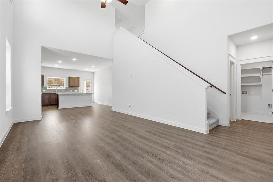 Spacious main living area featuring high ceilings, wood-finish flooring, and a ceiling fan