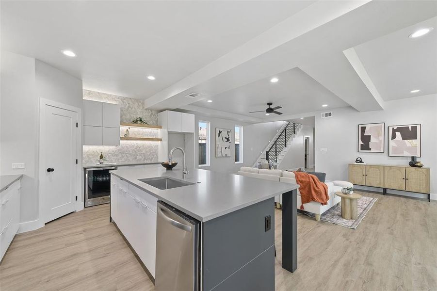 Kitchen featuring white cabinetry, a kitchen island with sink, dishwasher, oven, and sink