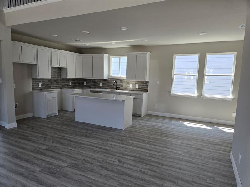 Kitchen featuring white cabinetry, tasteful backsplash, dark wood-type flooring, a kitchen island, and open floor plan
