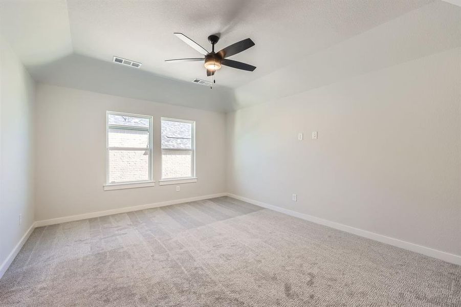 Carpeted spare room featuring ceiling fan and lofted ceiling