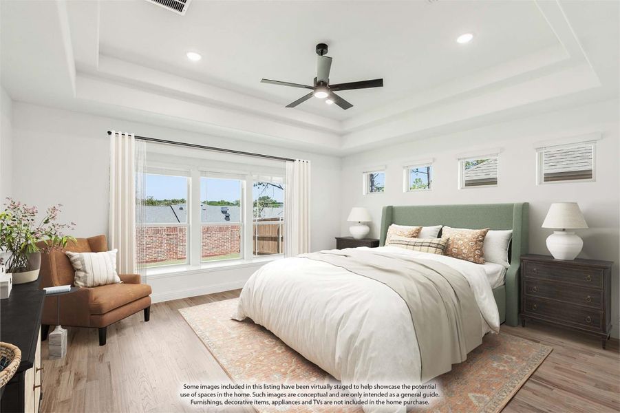 Bedroom with tray ceiling, ceiling fan, green upholstered headboard, hardwood floors, and large windows