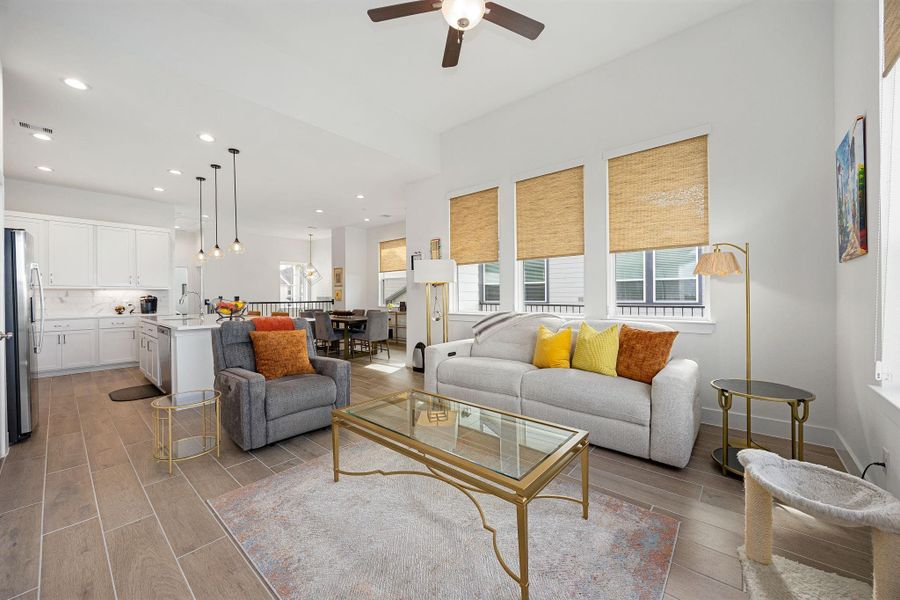 Living room area with wood look tile, custom blinds and updated fixtures.