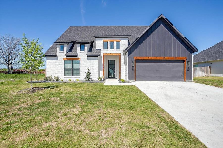 Modern inspired farmhouse featuring a garage and a front yard