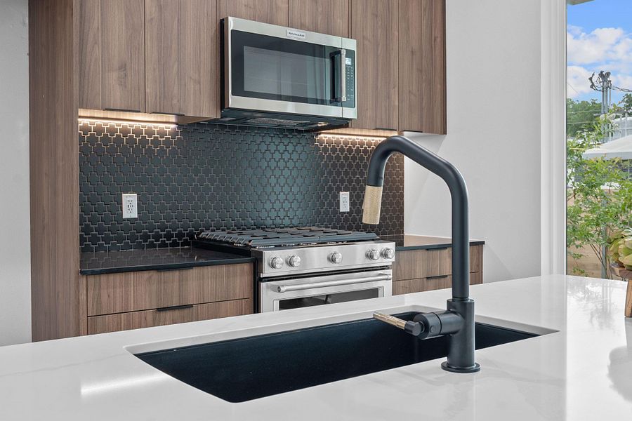 Kitchen featuring stainless steel appliances, modern cabinets, backsplash, and brown cabinetry