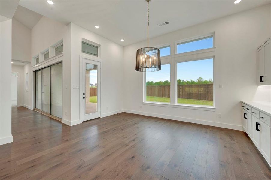 Dining area with a chandelier, dark wood-style floors, and plenty of natural light